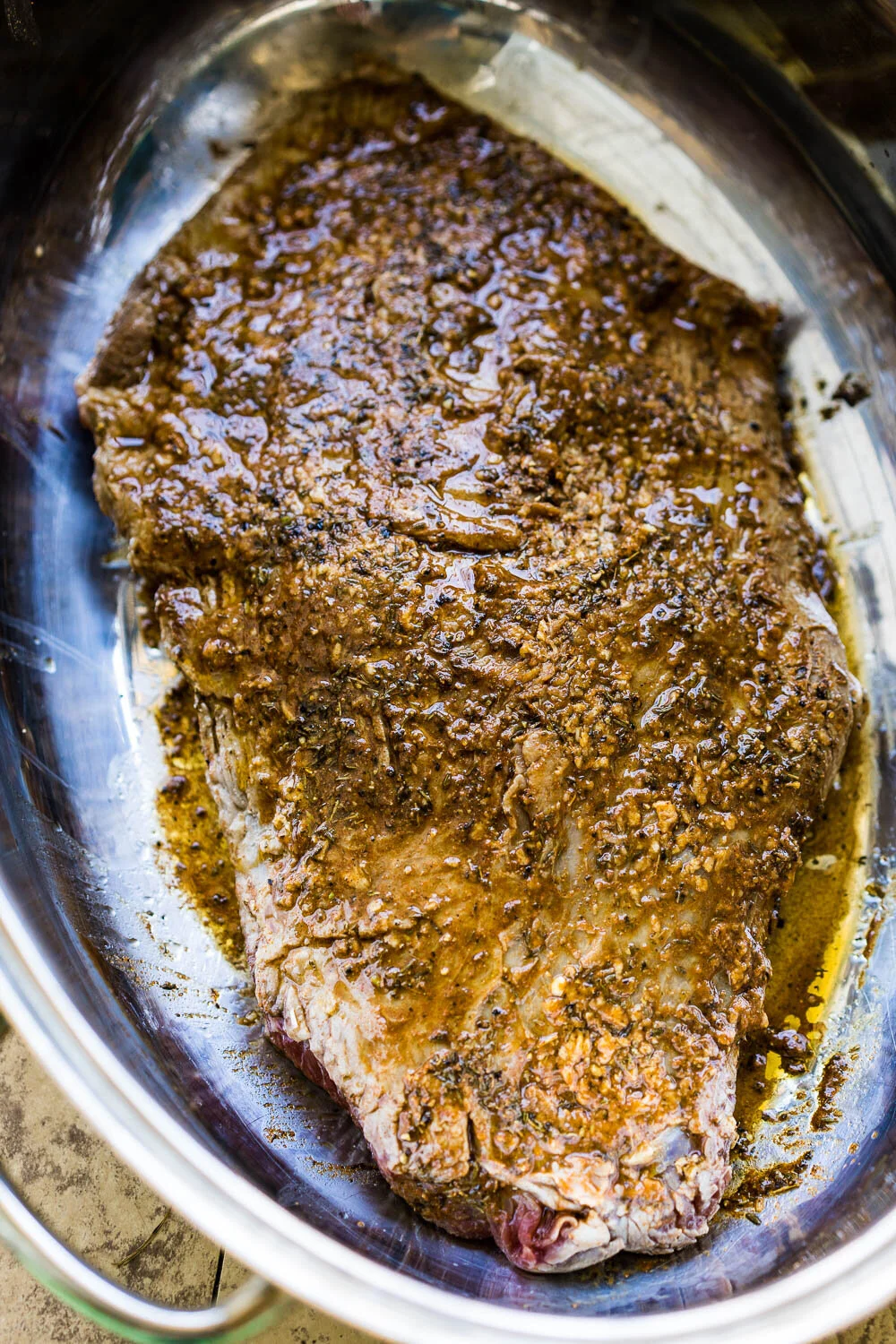 Brisket seared and coated in a flavorful thyme, sage, and paprika based marinade, awaiting the vegetables to go on top before roasting.