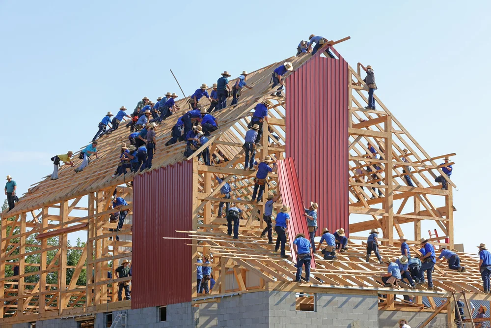 Photo by Randy Fath on Unsplash . Amish barn-raising with dozens of people working on the structure.