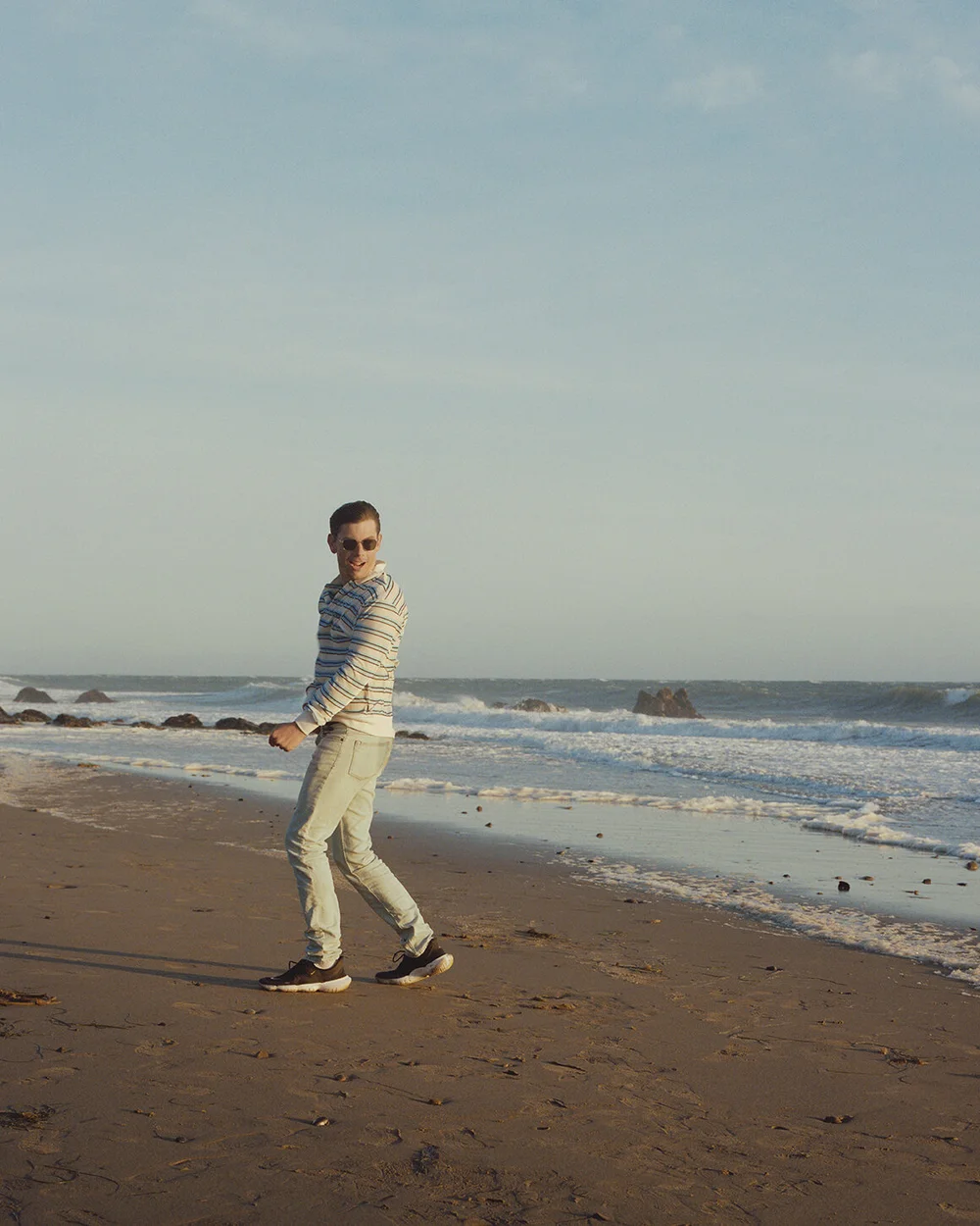 Noon Goons long-sleeve white and blue striped velour polo shirt, Acne Studios l ight blue denim jeans, Gucci belt, Uniqlo white ribbed cotton socks, Nike sneakers, RAEN sunglasses.