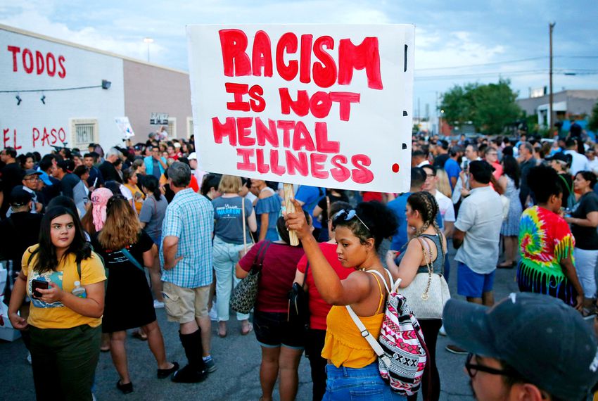 A woman holds a sign after a silent march to Las Americas Immigrant Advocacy Center for the victims of the Walmart shootings in El Paso August 4, 2019. Image via Michael Chow/The Republic via REUTERS