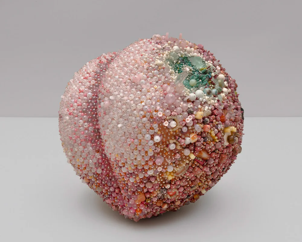 “Bad Peach” (2019), rose quartz, agate, carnelian, pink opal, rhodonite, rhodochrosite, calcite, amber, quartz, fluorite, tree agate, magnesite, turquoise, serpentine, bone, coral, jasper, tiger eye, labradorite, red malachite, mother of pearl, glass, steel pins on coated polystyrene, 15.5 x 16.5 x 16 inches