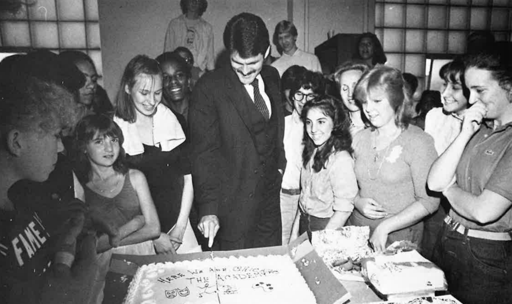 Larry Jordan cuts cake on the first day of school at The Academy, surrounded by excited students.