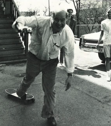 Richard "Solly" Sollenberger is in motion as he steps off of a skateboard. He has noticed the camera, and is smiling at it. Taken in 1985.