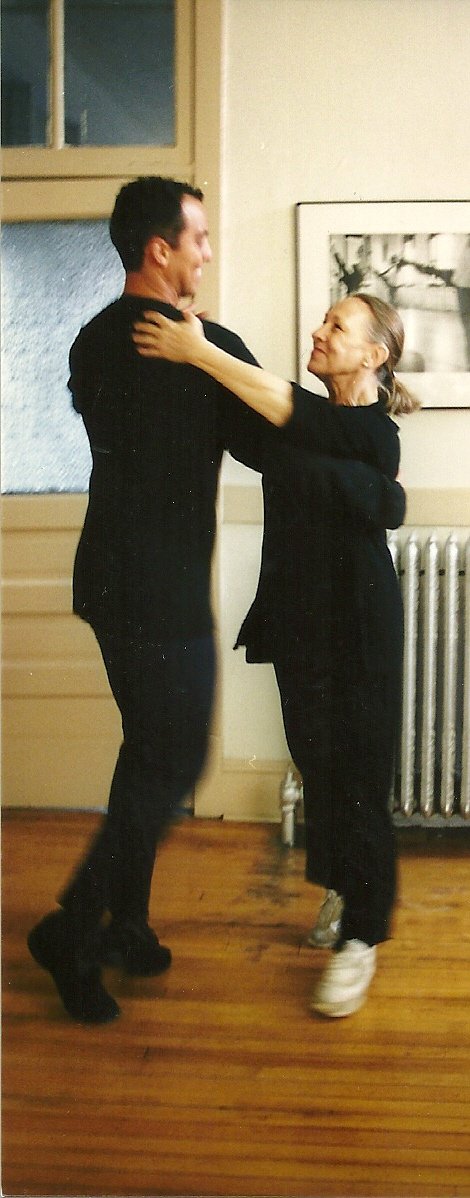 Eduardo Vilaro (left) and Anna Paskesvka share a dance in the halls of The Academy. Anna has her arms on Eduardo's shoulders, and they are in motion.