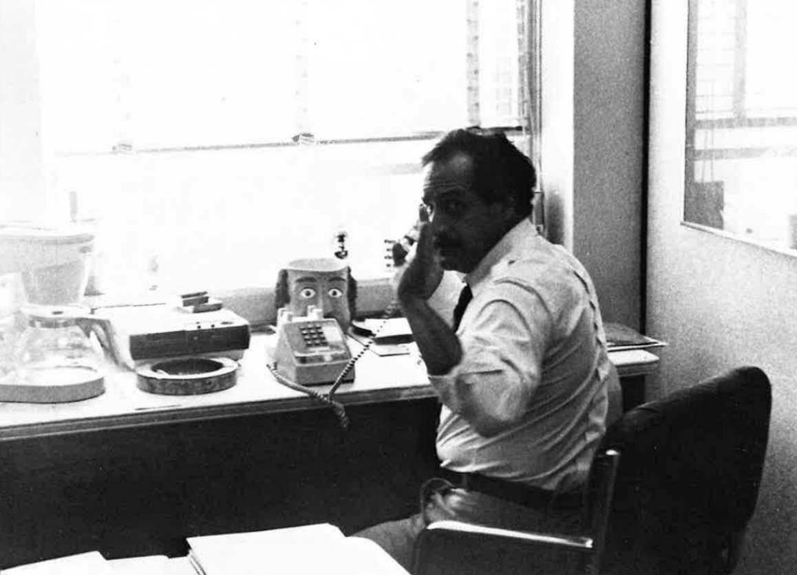 弗兰克·穆斯塔里坐在学院的办公桌前.