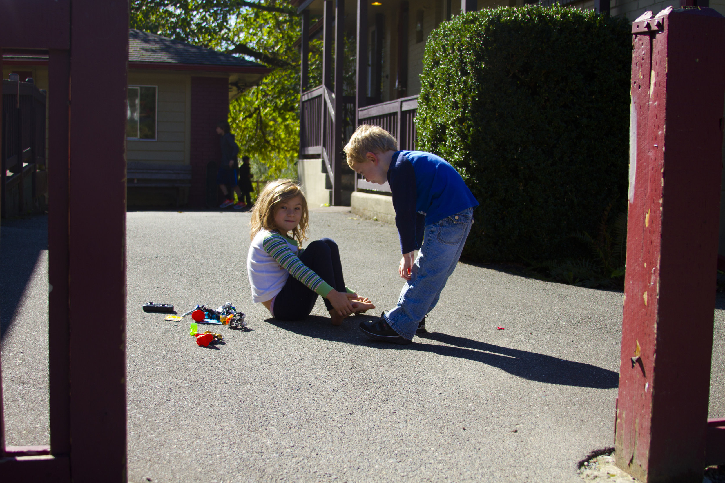 Two young students play with small toys outside.