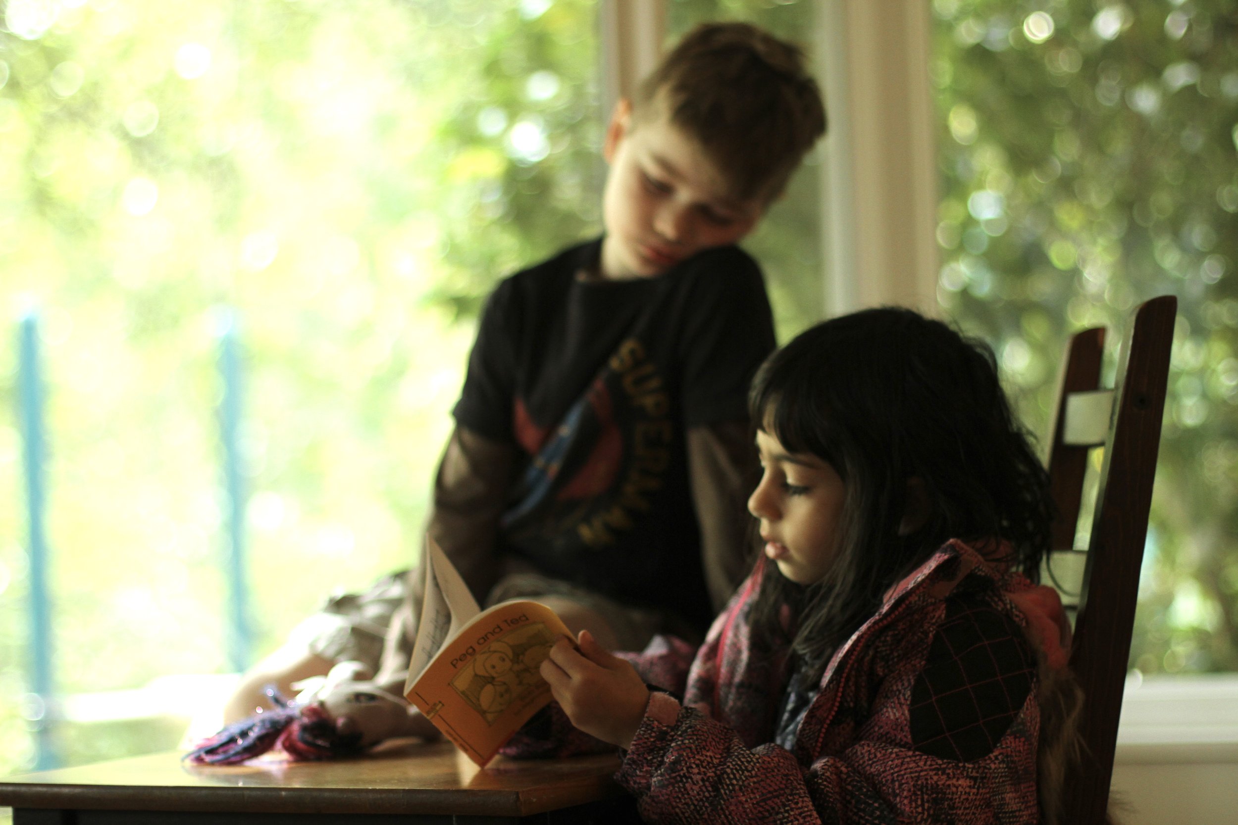 Two young students reading a book together.