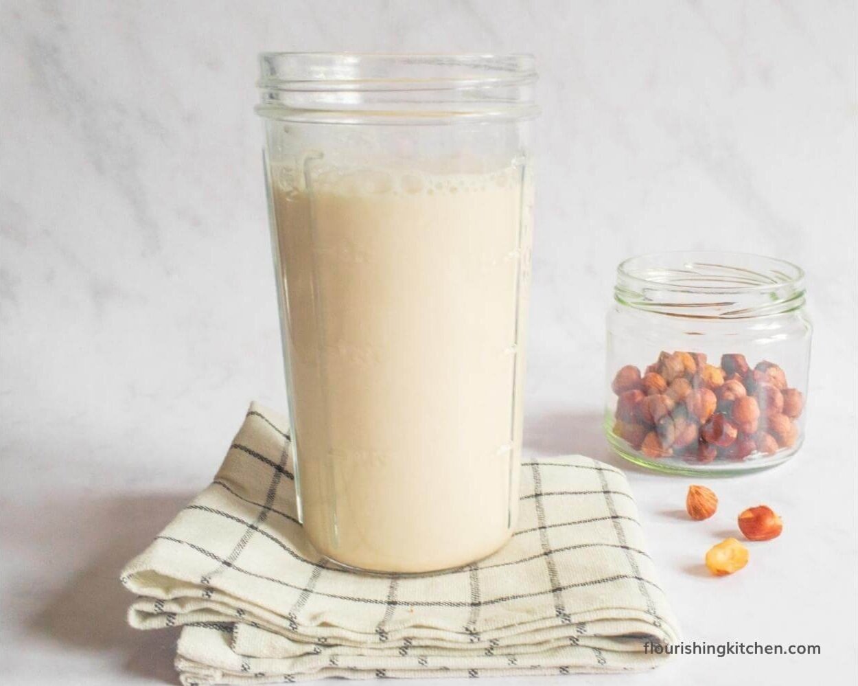 未加工的自创榛子牛奶在一个高梅森瓶子,坐茶毛巾。 #hazelnutmilk #rawhazelnutmilkrecipe