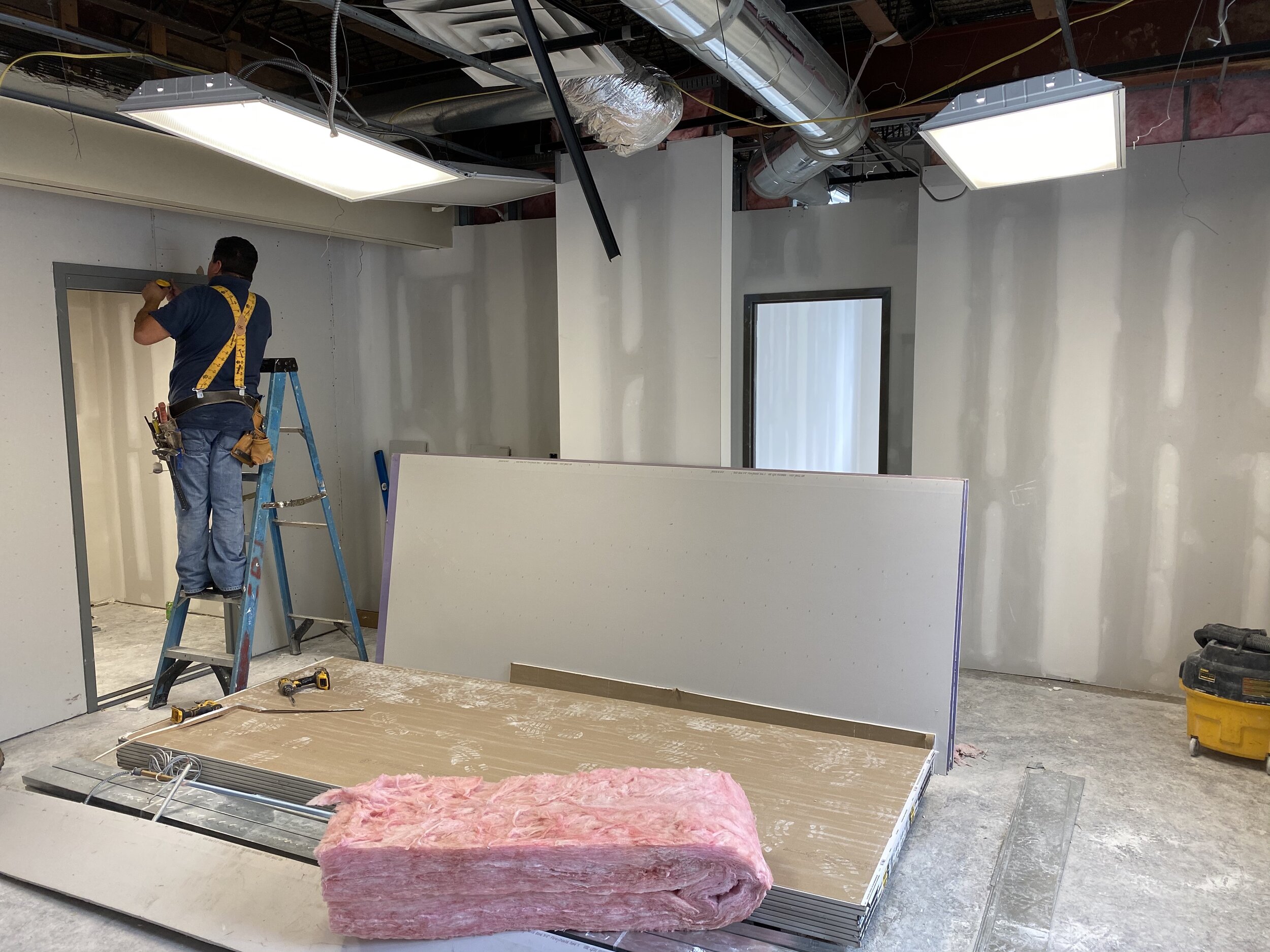 workers are installing a door in the new school office area.