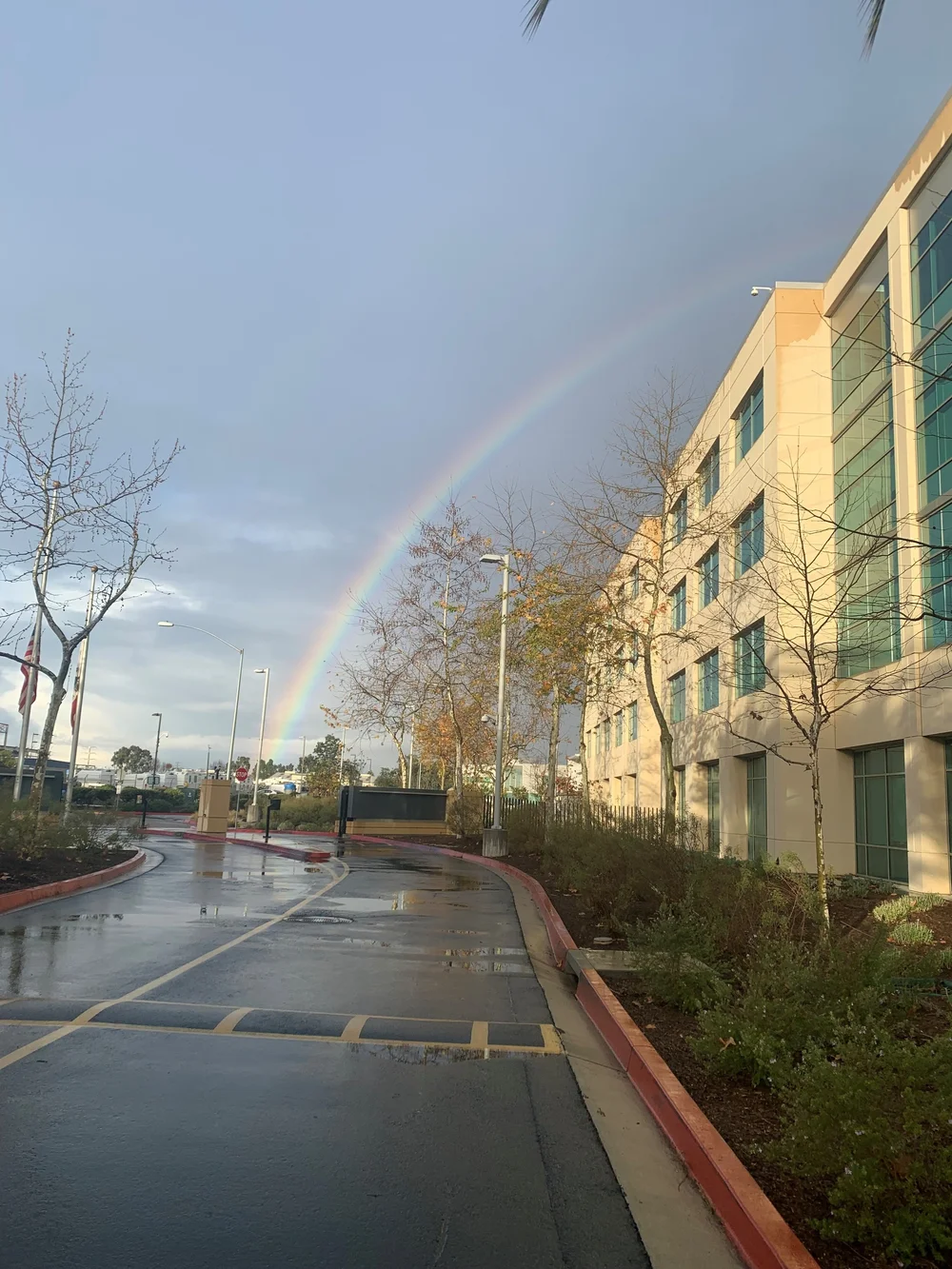 rainbow in the distance over a driveay and building