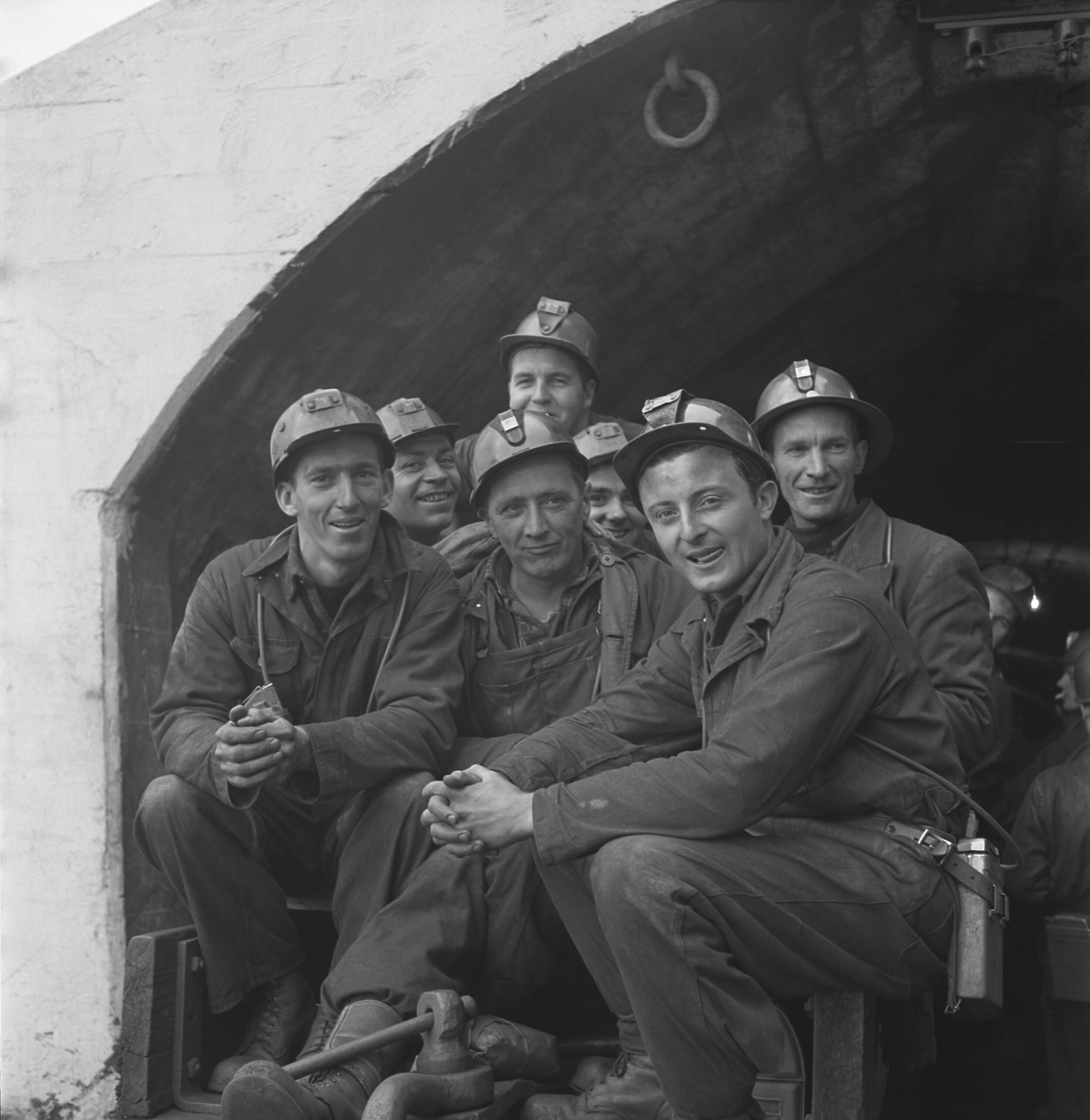 GH_070_0229:1940-2013“NF:Bell Island - 铁未成年人  七个未成年人的小组照片。“ - “NF:贝尔岛 - 铁矿工" - 用案例写的手描述:一群七元的黑白图象携带耳机坐在隧道入口外面的托架上。