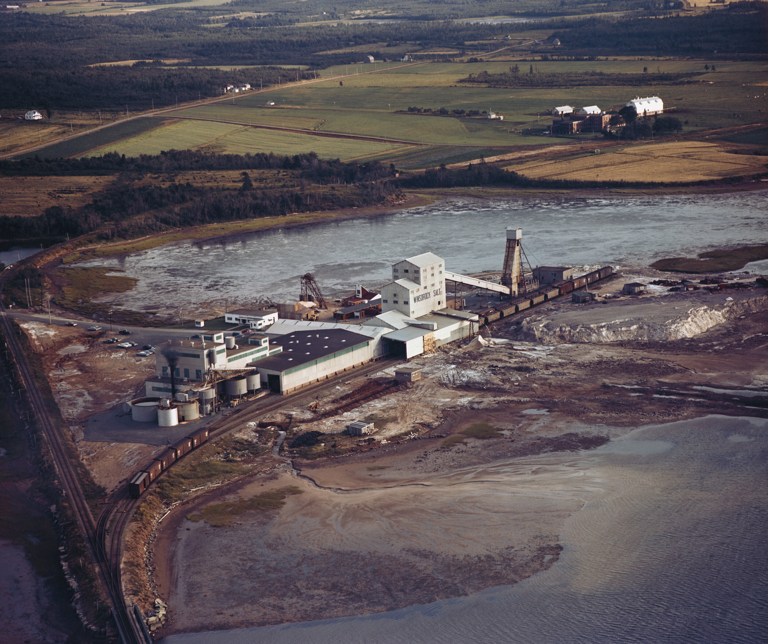 GH_080_0130_A:1940-2013“加拿大盐有限公司Winsorock Pugash Salt Mine。新苏格兰“ - "加拿大盐有限公司WINSOROCK SALTIN PUGWASH。新斯科舍省" - 在案例描述的标签上盖章:加拿大盐公司的彩色空中照片,中间。海滩和海洋位于前景,邻近的农场在后台。