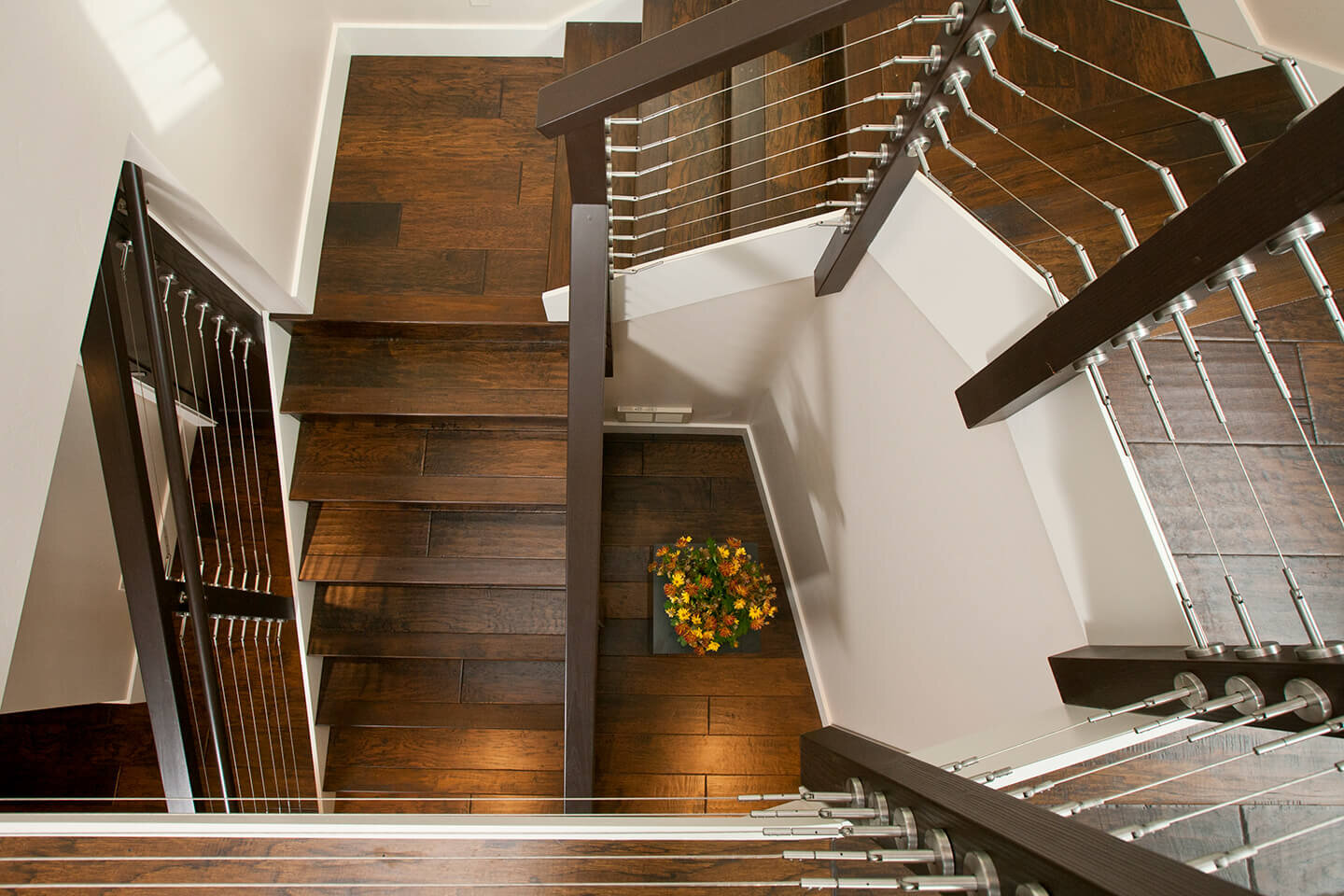 Staircase with steel cables and dark engineered wood flooring