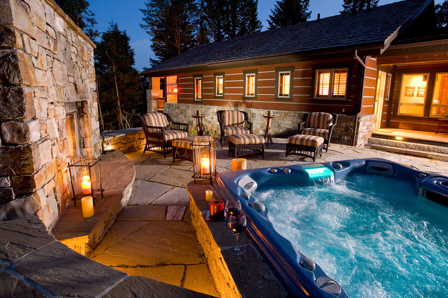 Outdoor blue water jacuzzi by stone wall at night