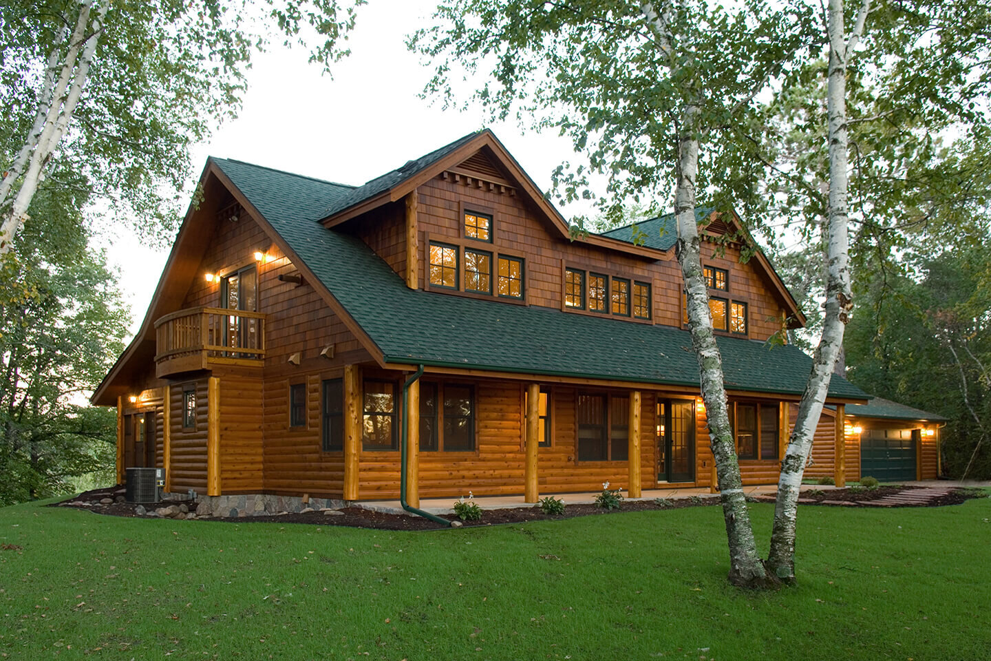 Lit up log home with lawn and aspen trees