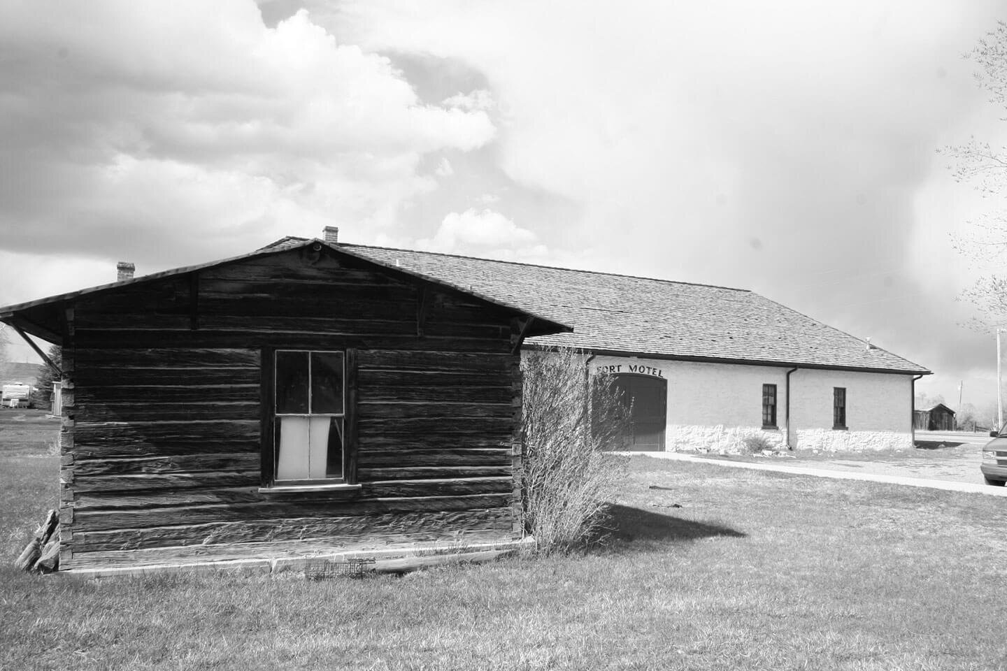 Historical log cabin next to white structure