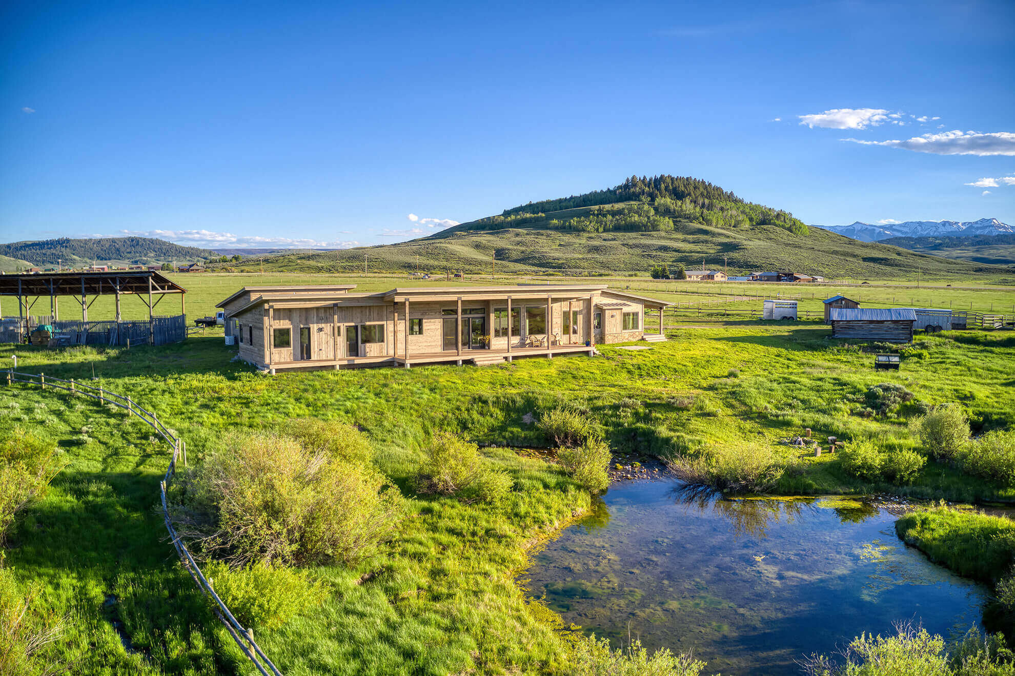 Western facade in spring with hay shed and pond