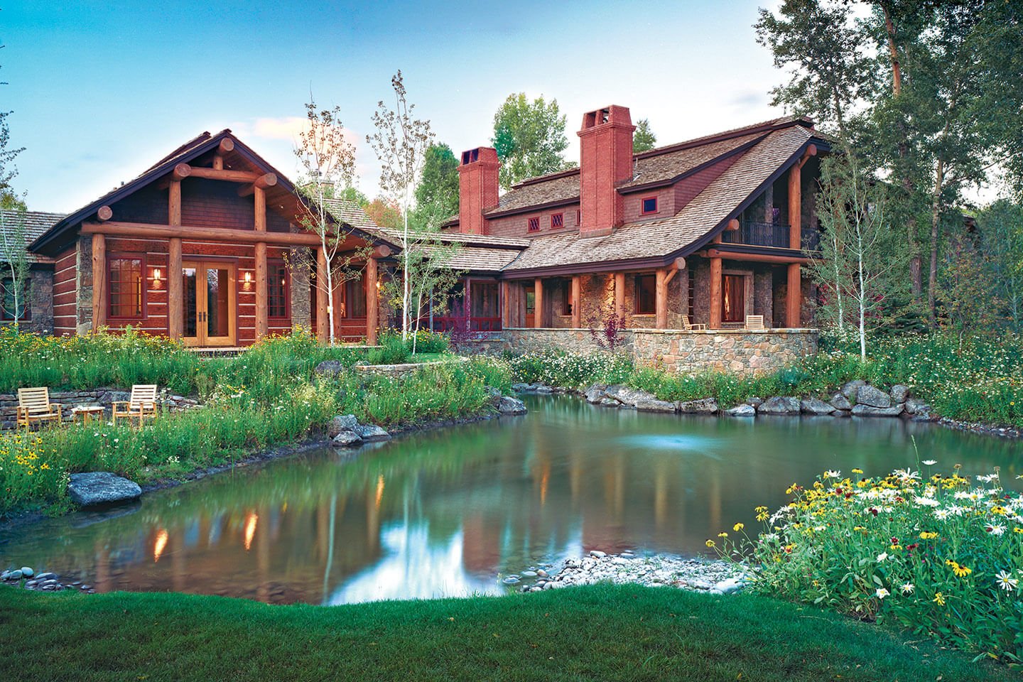 log home with brick chimney, by a pond