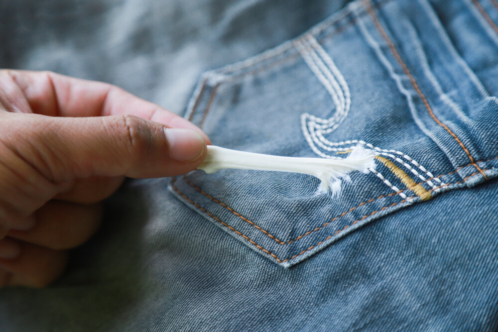 用手拉口香糖粘在牛仔裤上清洗. 脏污渍在布料上的概念