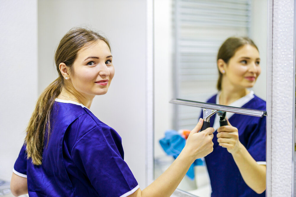 一个穿着清洁服务制服的女孩在清洁浴室里的镜子. 清洁消毒的理念.jpg