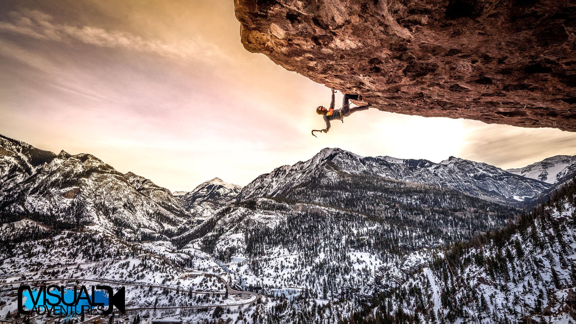 Ice climber on an over hang mountains in the background