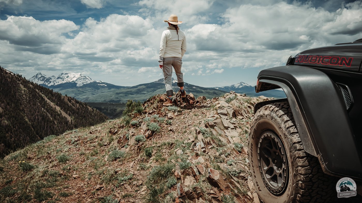 Man looking over mountain edge with jeep in foreground