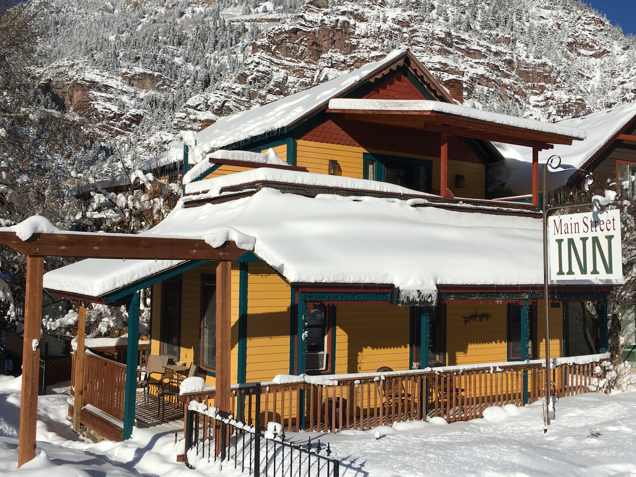 Yellow house with snow on roof