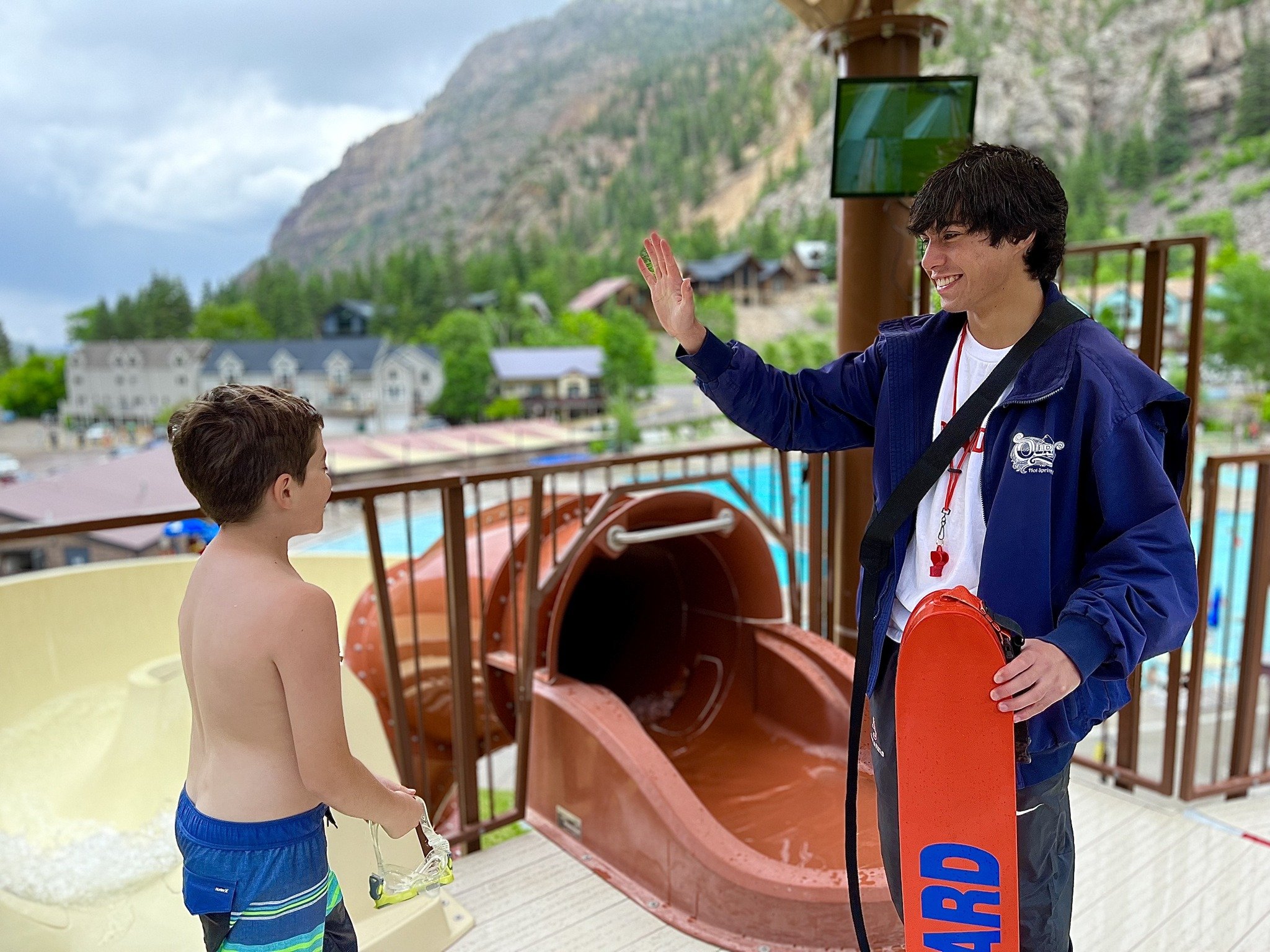 Life guard high fiving boy on waterslide
