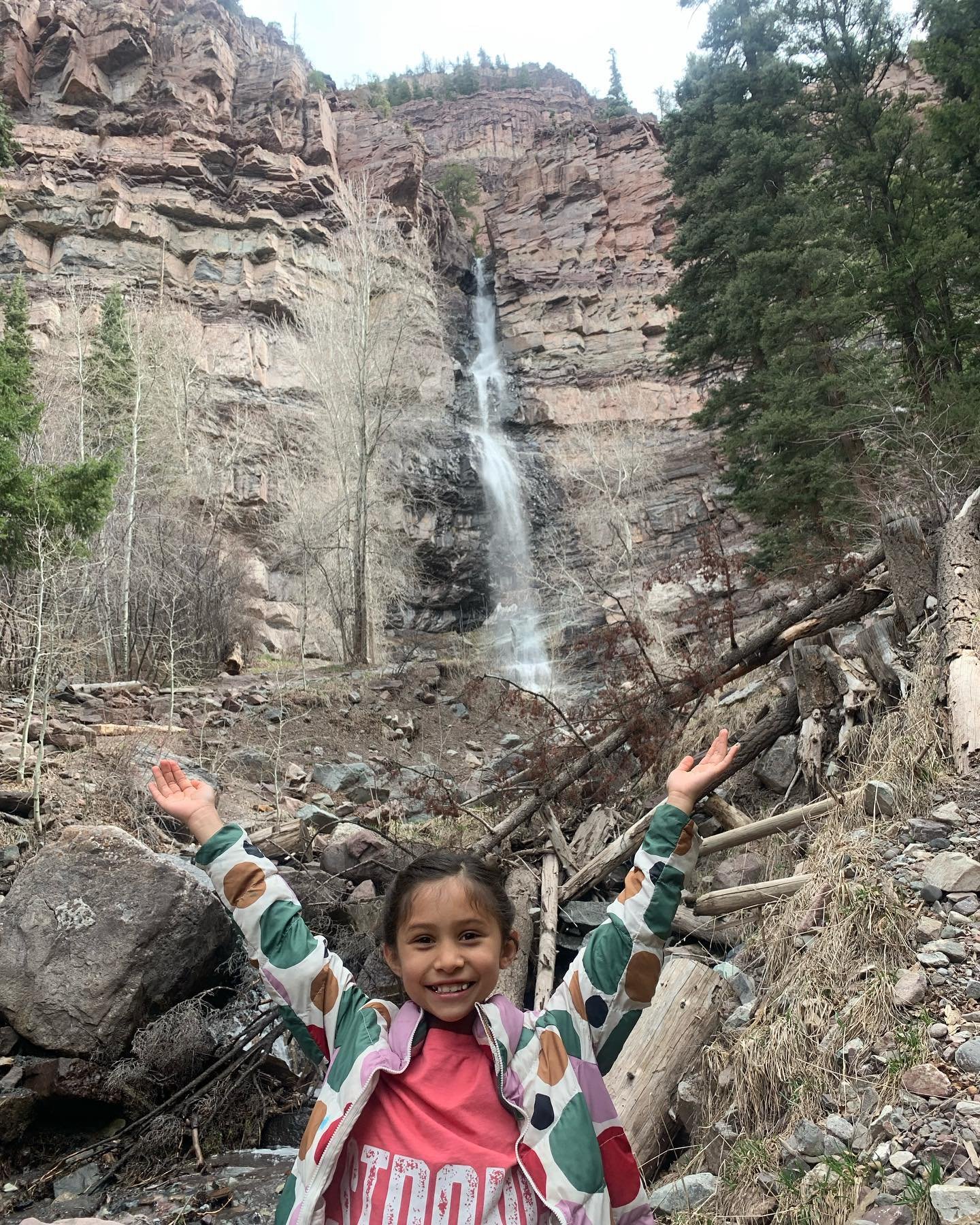 Girl with her arms up and waterfall in the background