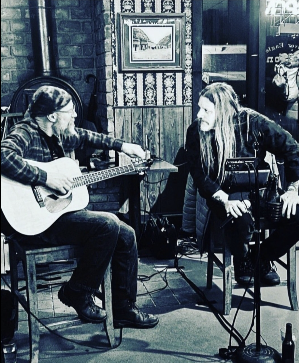 Two guys, one singing one on a guitar