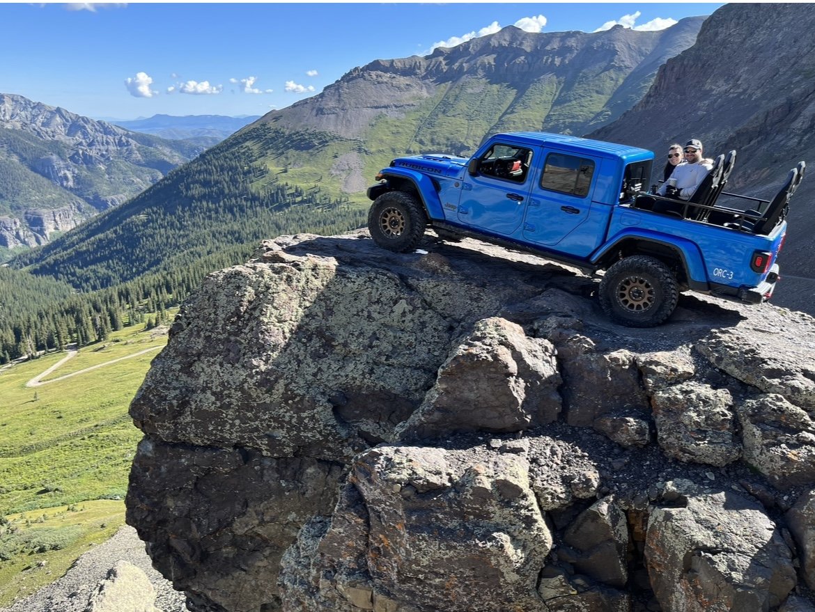Blue jeep on rock in mountains