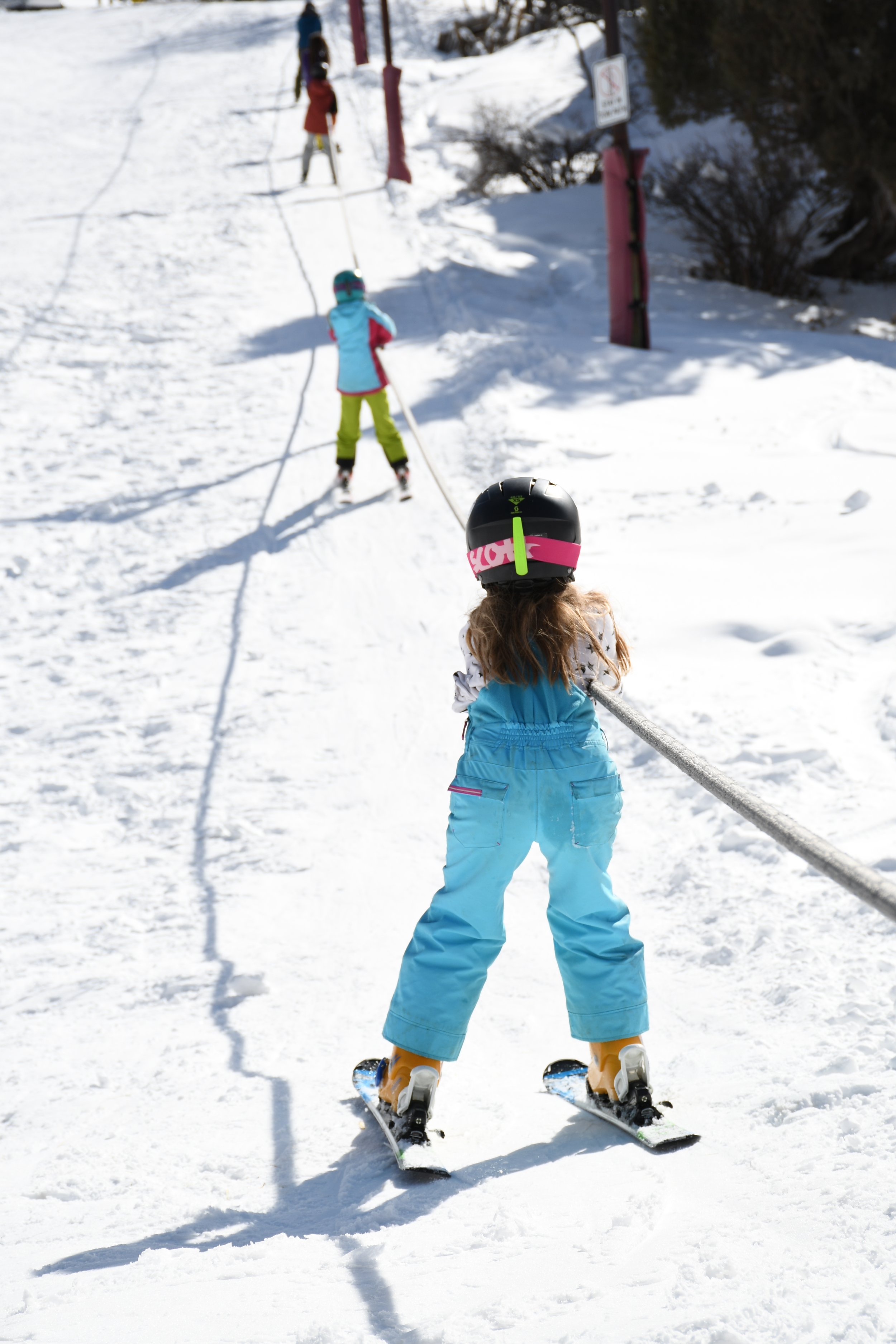 小女孩在滑雪板上抓着拖绳