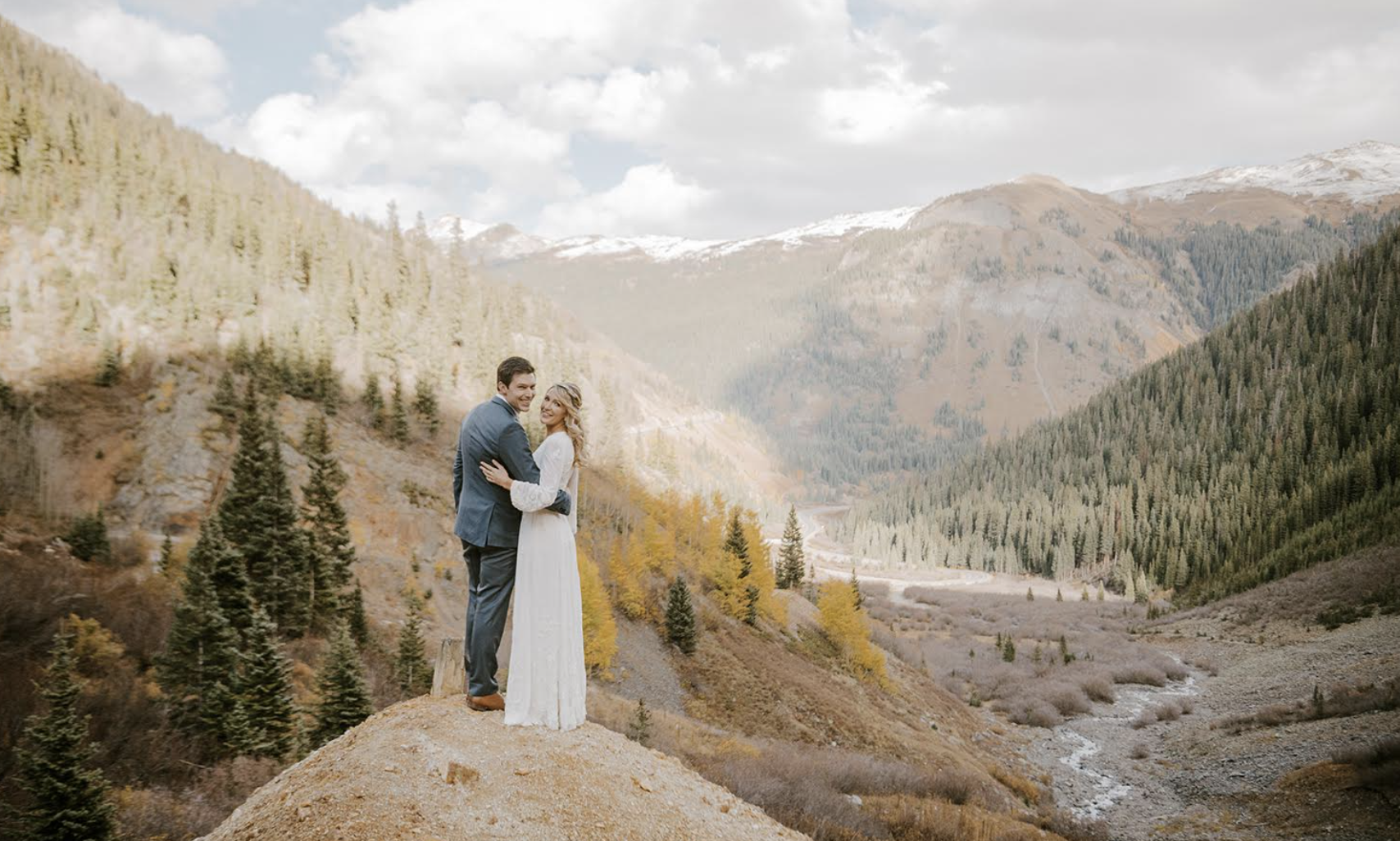 Couple in wedding attire posing in mountains
