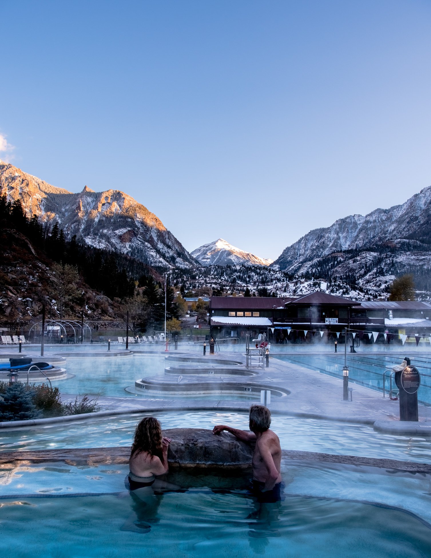 Two people in hot spring looking at mountains
