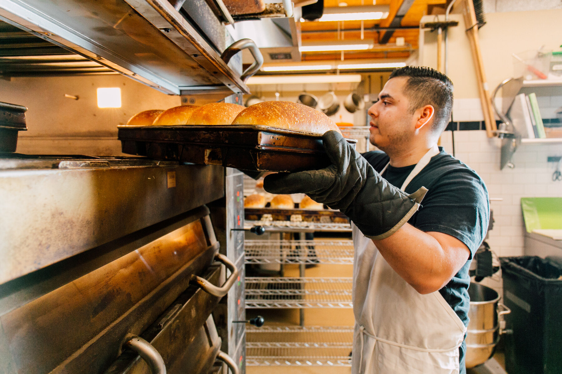 在斯卡吉特山谷食品十大赌博靠谱网络平台面包店，面包师正在从烤箱中取出面包