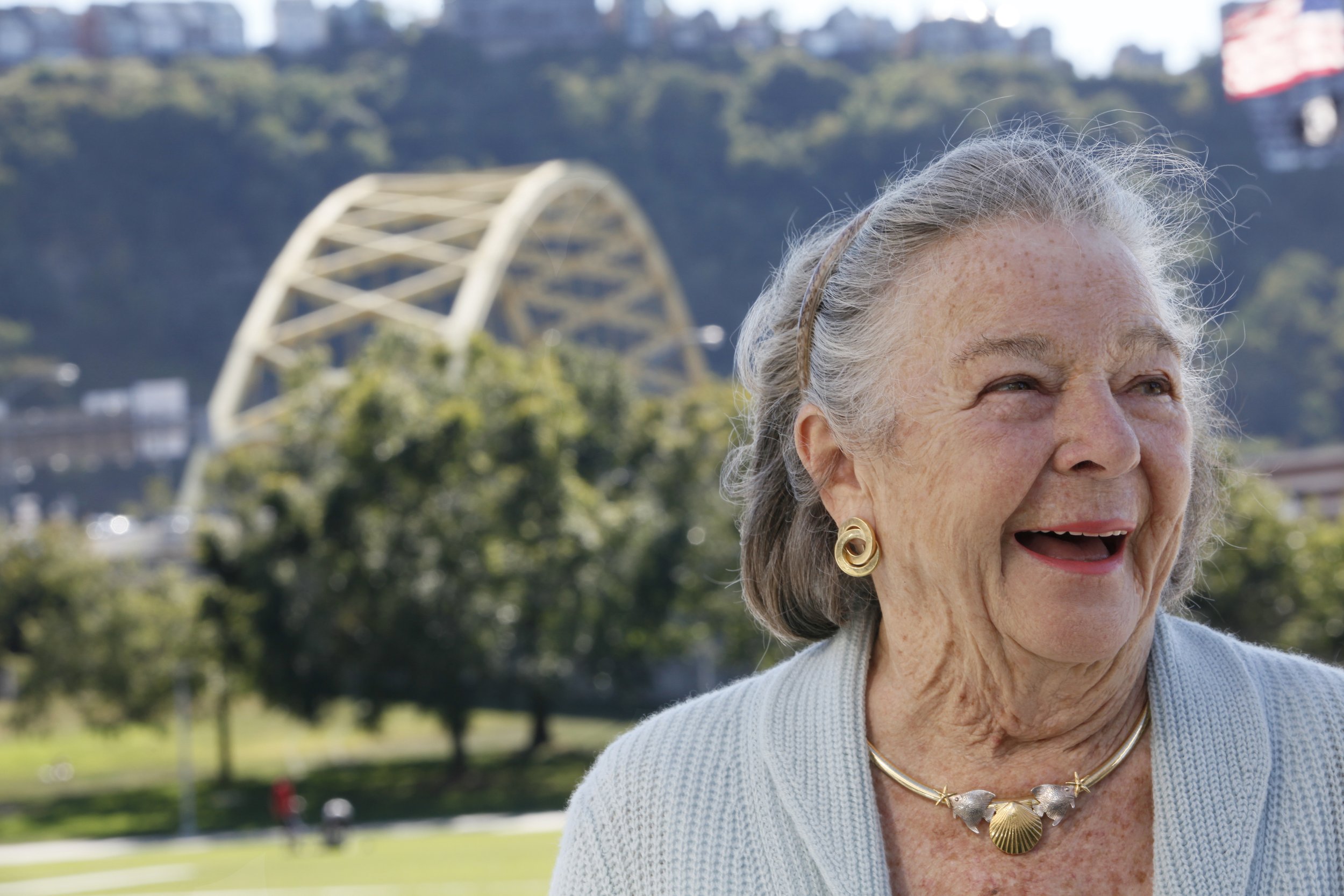 Photo from Riverlife Magazine of Elsie Hillman, an elderly white woman posing in front of a yellow Pittsburgh bridge