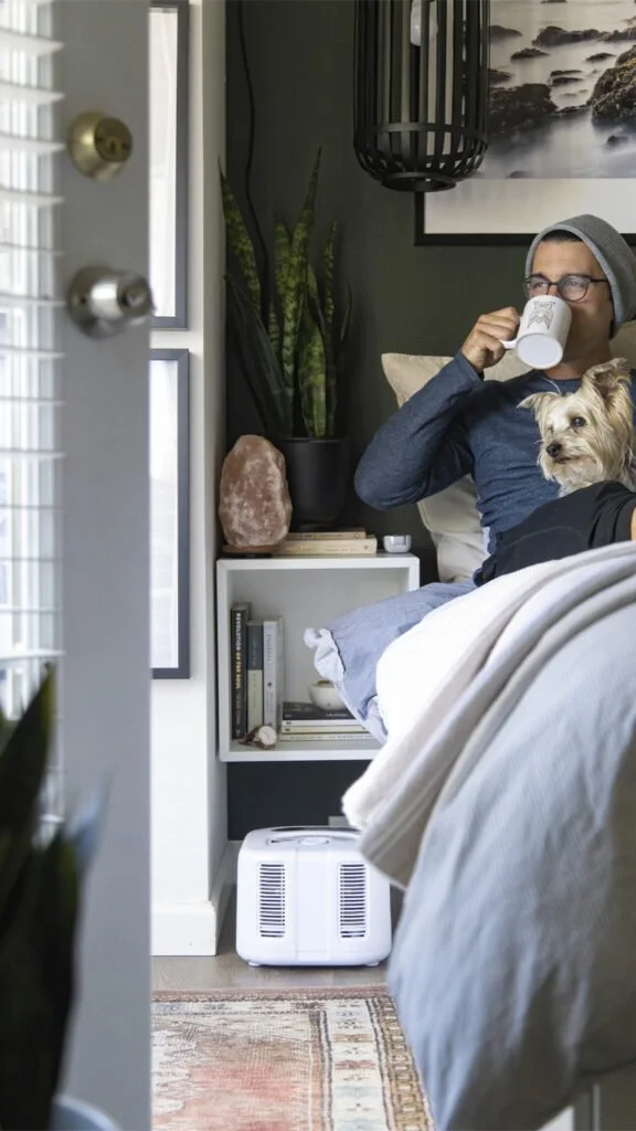 man drinking coffee in bed with dog on lap looking outside. chilipad system