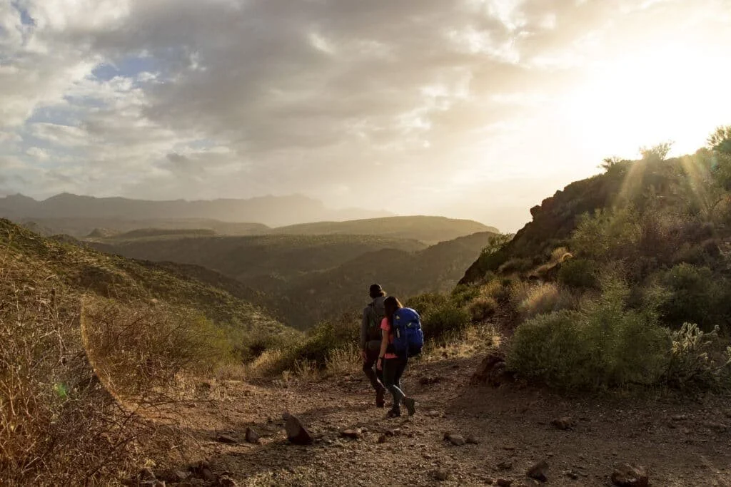 A couple on a backpacking trip with dramatic lighting in the Sonoran Desert