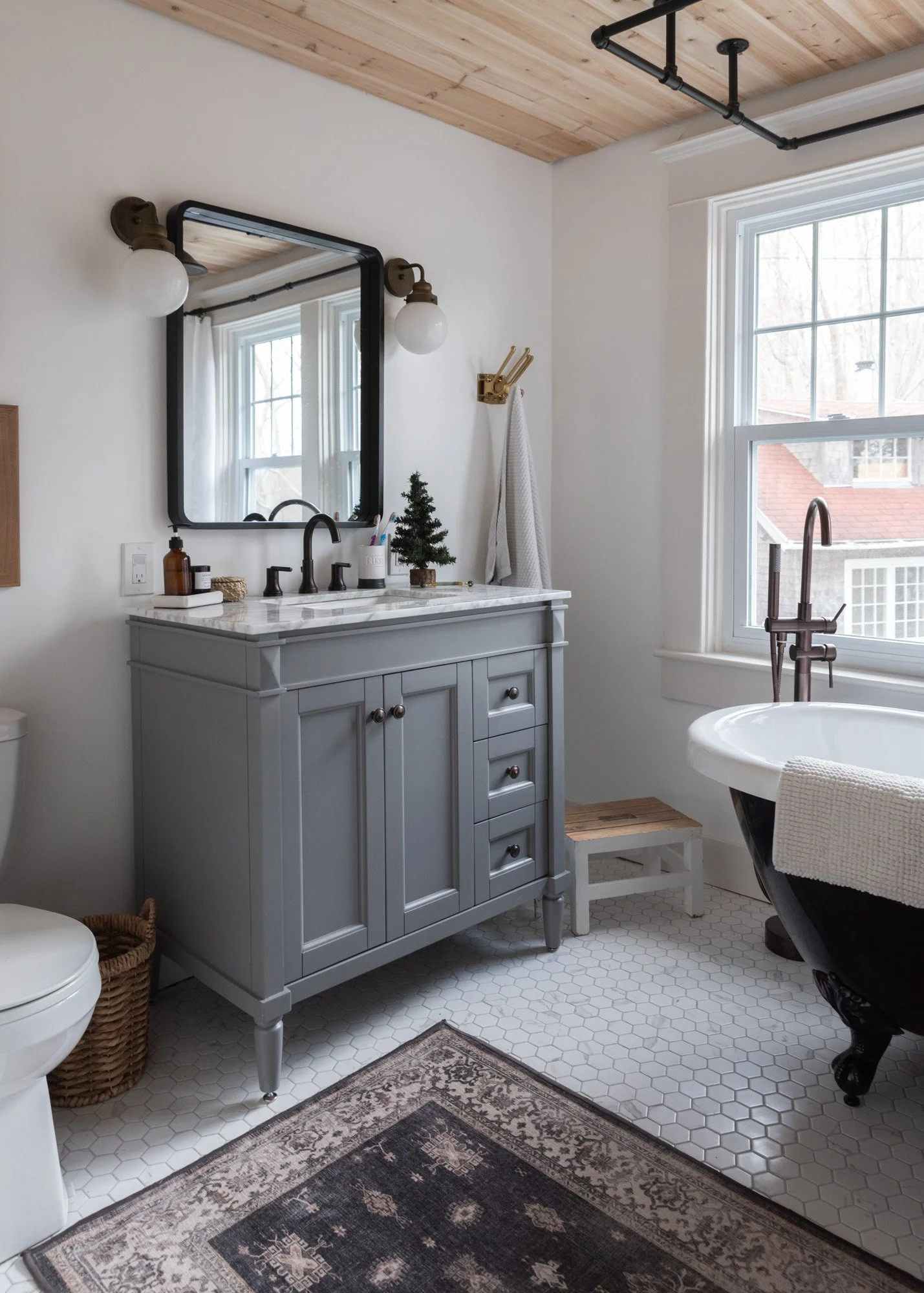 The Wild decoelis | 2020 Holiday Home Tour | Gray vanity with marble countertop, marble hexagon floor tile, rugggable Rug, black clawfoot tub gold fixtures
