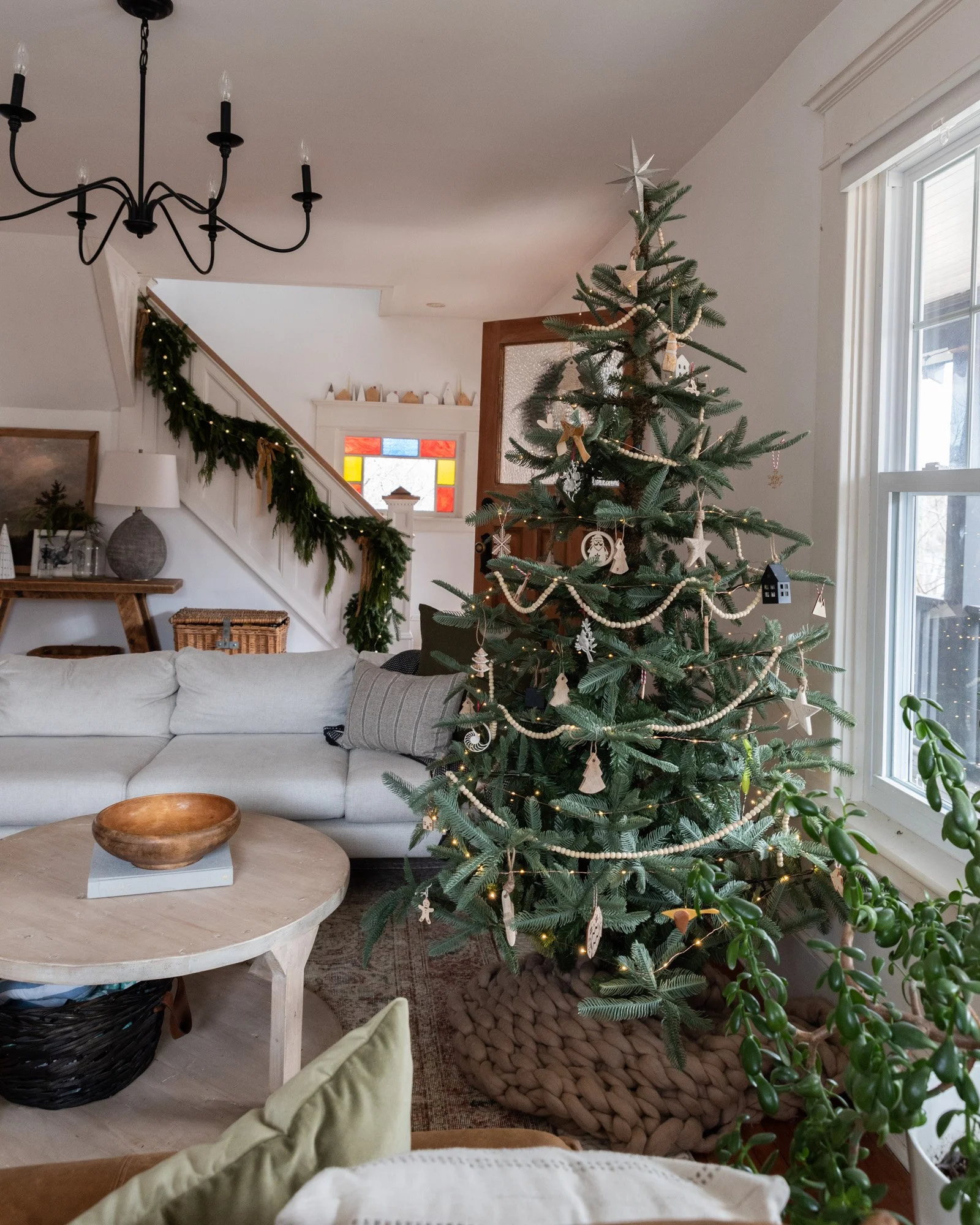 The Wild decoelis | 2020 Holiday Home Tour | King Of Christmas Noble fir tree With twinkle lights wood beads wooden ornaments, pewter ornaments and real Cedar and Pine garland. White couch, knitted blanket as a tree skirt