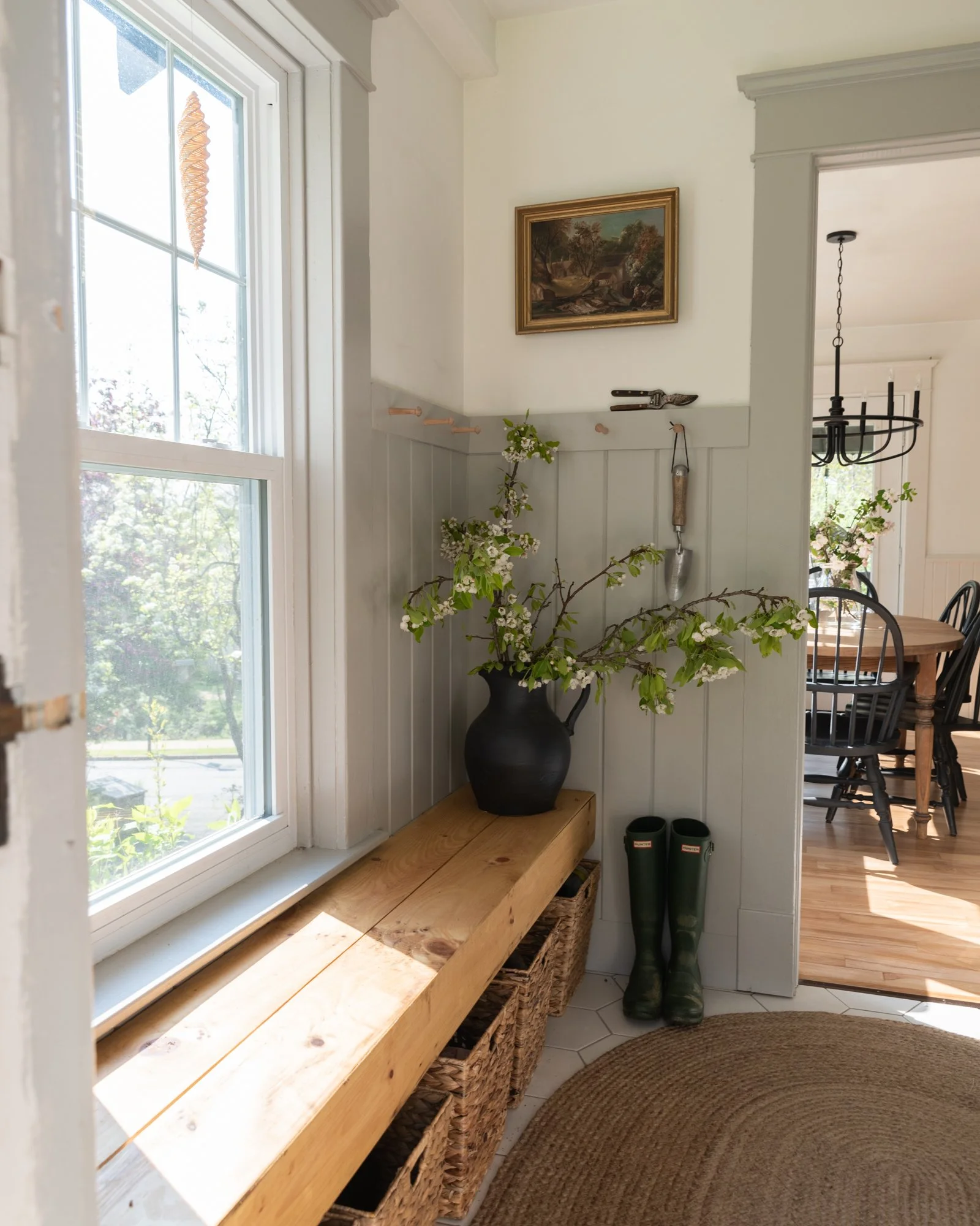 the wild decoelis | apple blossom branches in the house as decorations. Built in bench, refinished wood floors, black chairs, baskers, black vase, black chandelier, vintage art.