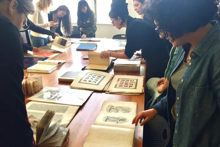 Group of people standing around a table and looking at books displayed on the table.