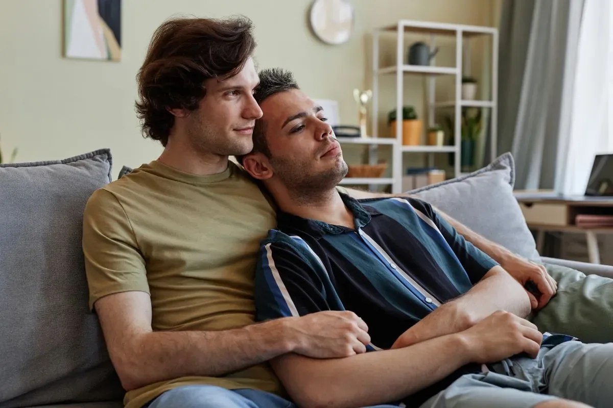 Two partners sitting close and at ease on a sofa at home, reflecting the calm of a supportive couples therapy space