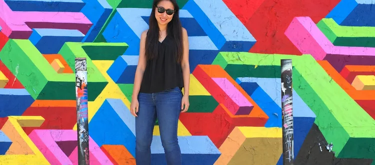 Natasha smiling in sunglasses in front of a colorful mural