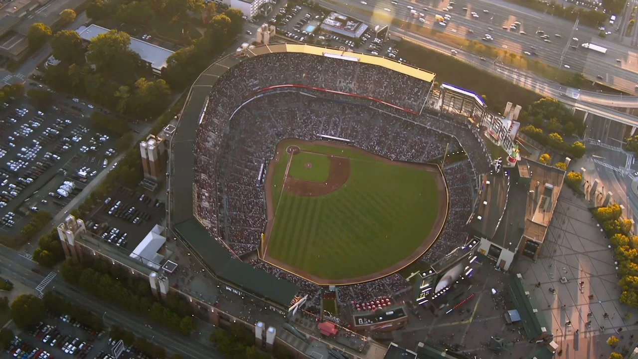An aerial view of a full baseball stadium in warm evening light, from the MLB customer film.