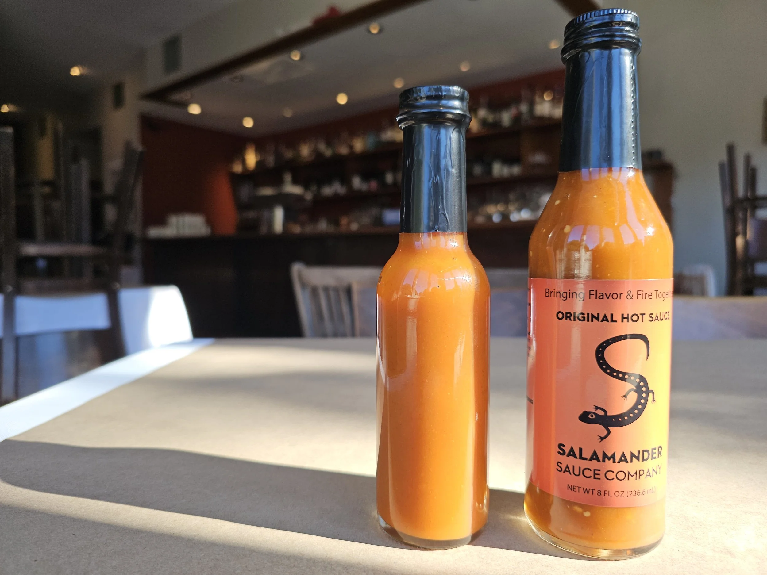 Salamander Sauce 8oz bottle next to industry standard 5oz hot sauce bottle