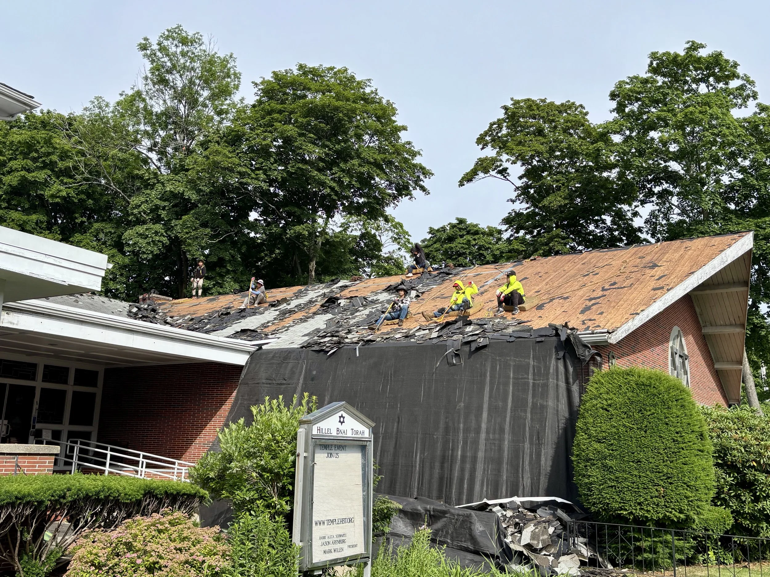 Roofers removing the old shingles from Temple HBT's roof down to the deck