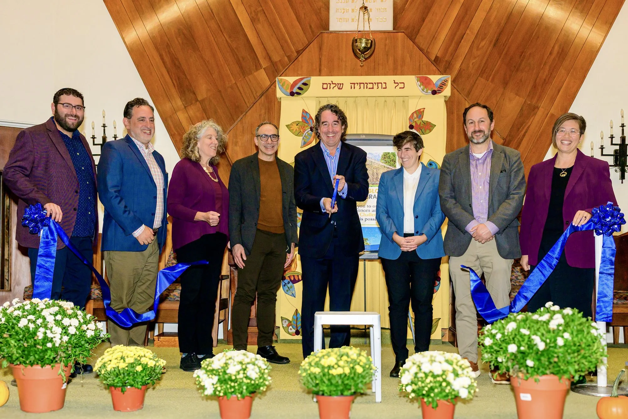A moment later, everyone on the bimah beams, each end of the cut ribbon now hanging free.