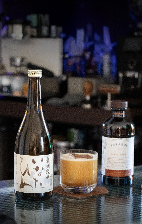 Test One coffee cocktail on the rocks beside a sake bottle