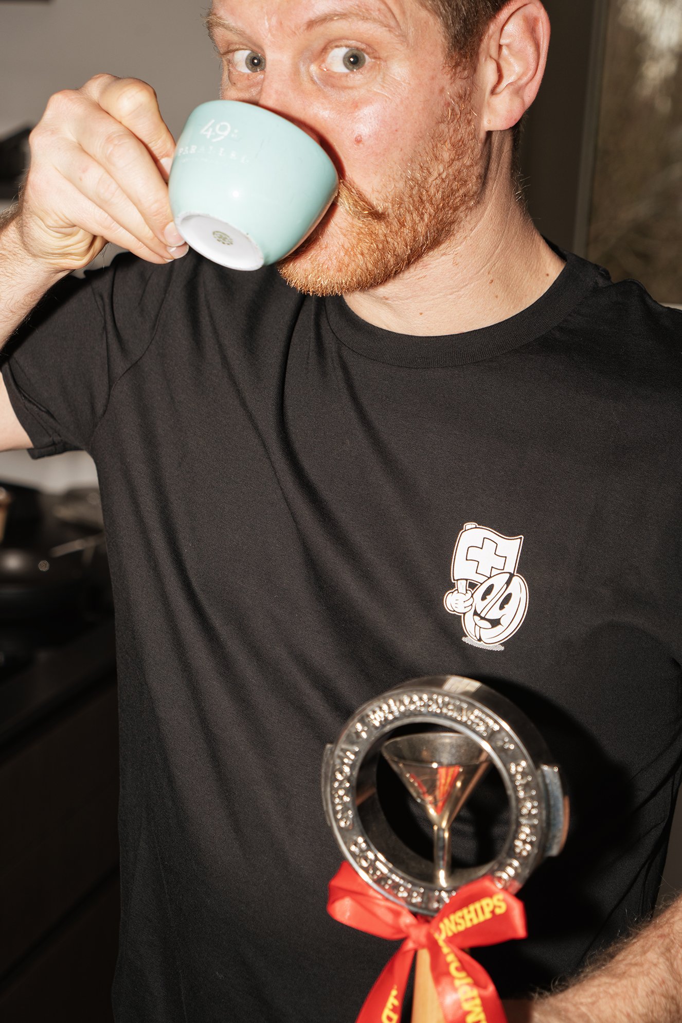 Sandro Roth sipping an espresso while holding a Coffee in Good Spirits trophy